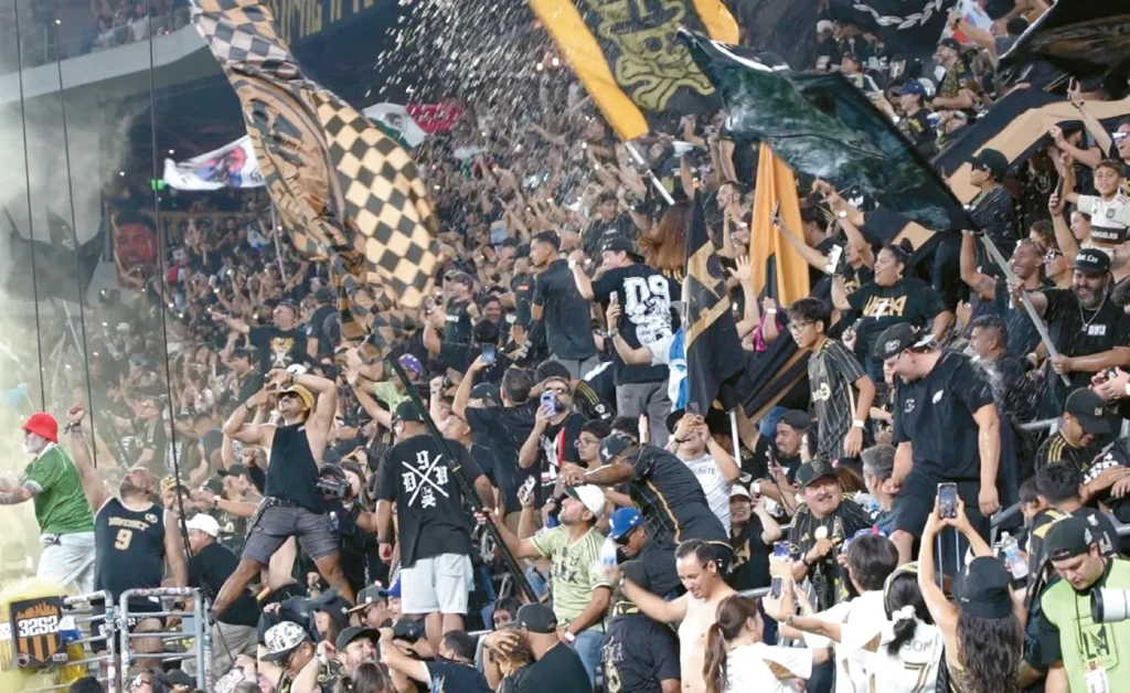 LAFC 팬들이 유니폼을 입고 경기장에서 응원하는 장면. LAFC 팬들이 유니폼을 입고 경기장에서 응원하는 장면.